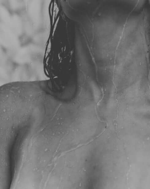 Woman in shower with blurred water overlay — illustrating how hard water affects skin