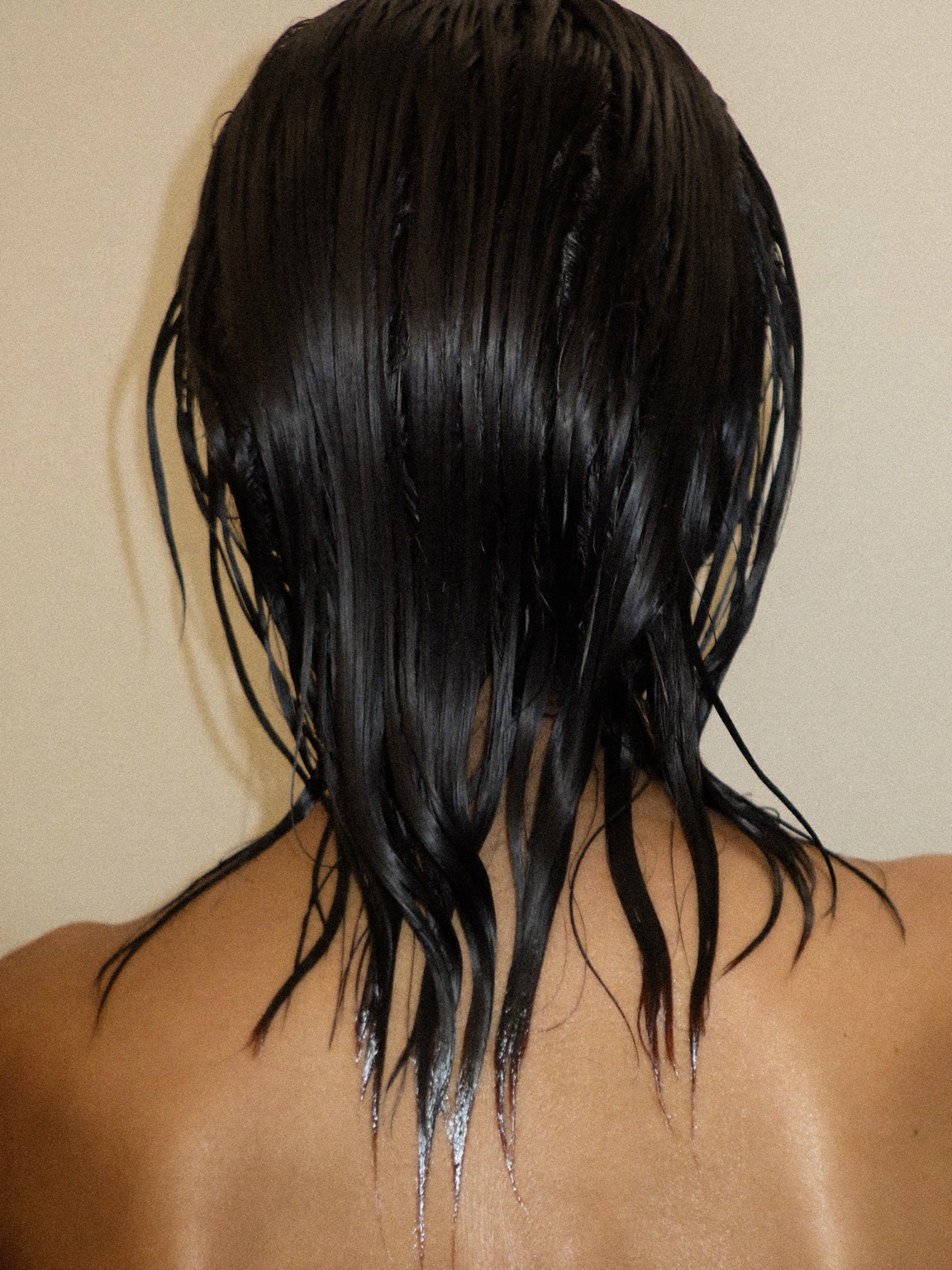 Back view of wet dark hair after washing in the shower
