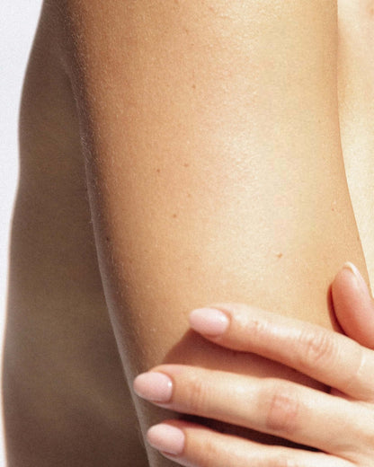 hand using exfoliating mitt in shower to remove dead skin